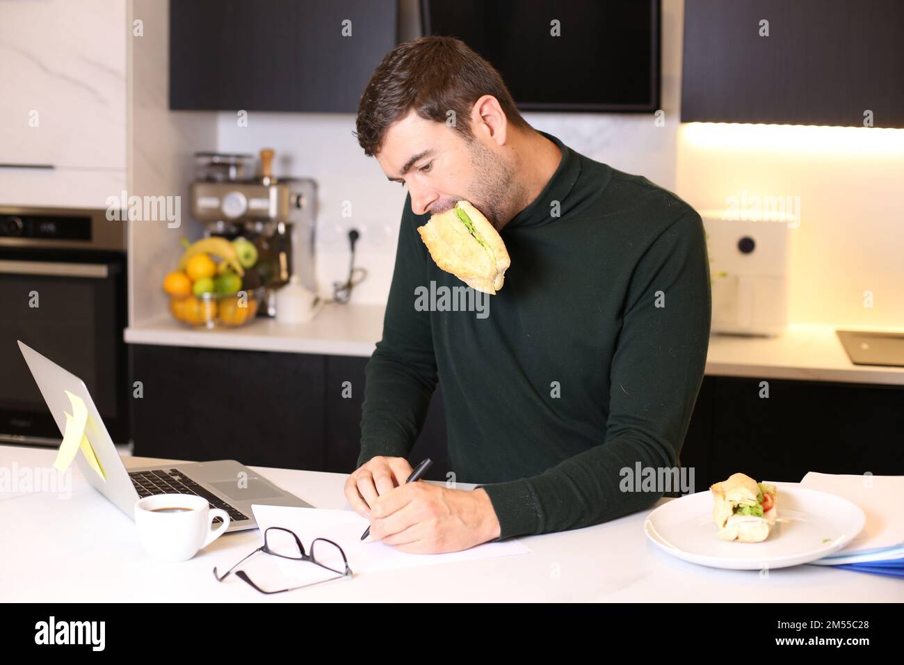 Homme occupé mangeant un sandwich pendant la conférence téléphonique Banque D'Images