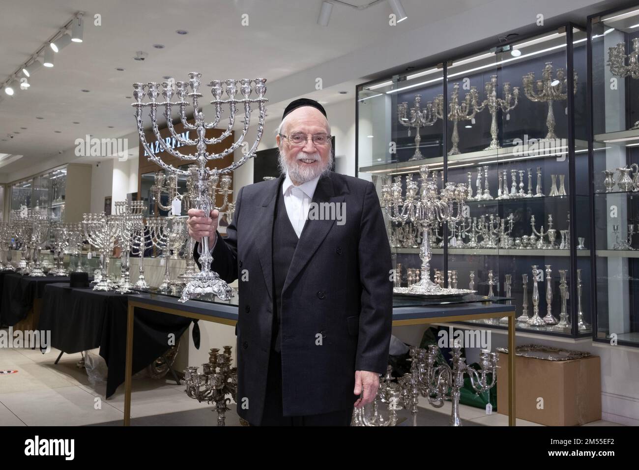 Portrait d'un juif orthodoxe qui exploite un magasin vendant des objets religieux en argent. Ici, il tient une belle menorah. À New York. Banque D'Images