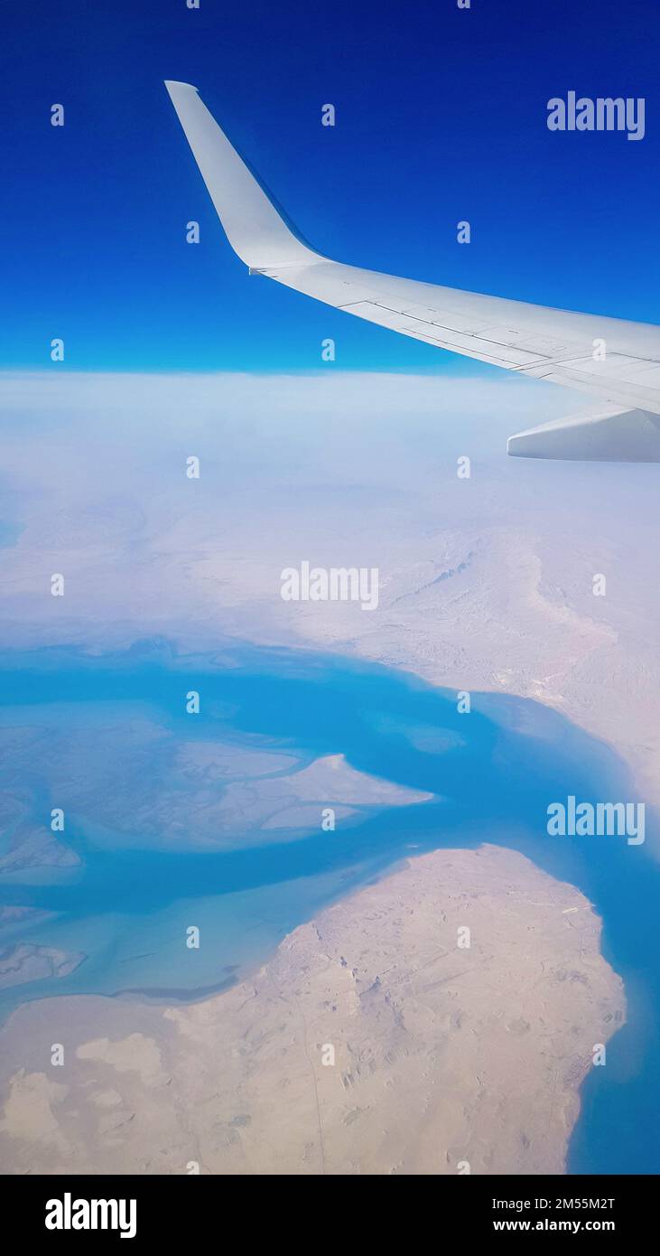 Vue de la fenêtre de l'avion sur le ciel bleu et la terre avec paysage de désert, mer et canaux dans les Émirats. Photo de haute qualité Banque D'Images