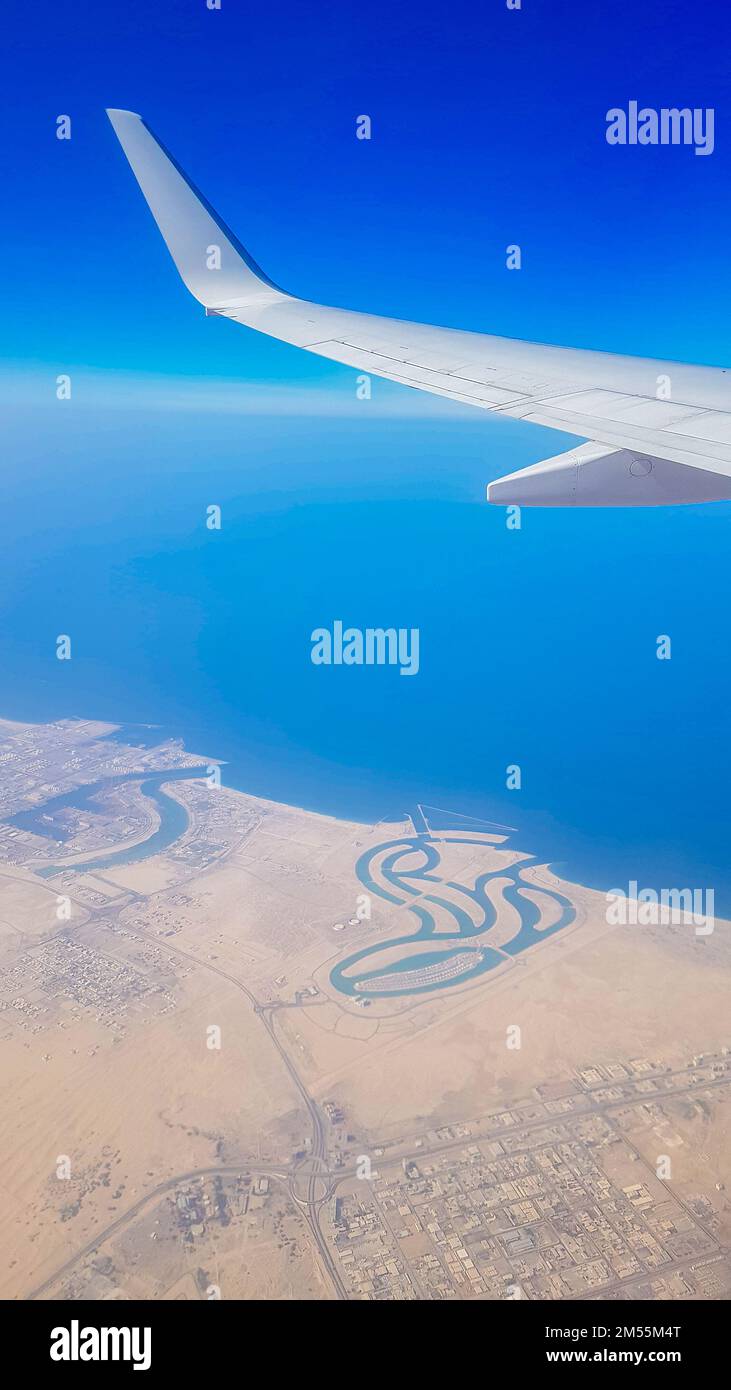 Vue de la fenêtre de l'avion sur le ciel bleu et la terre avec paysage de désert, mer et canaux dans les Émirats. Photo de haute qualité Banque D'Images