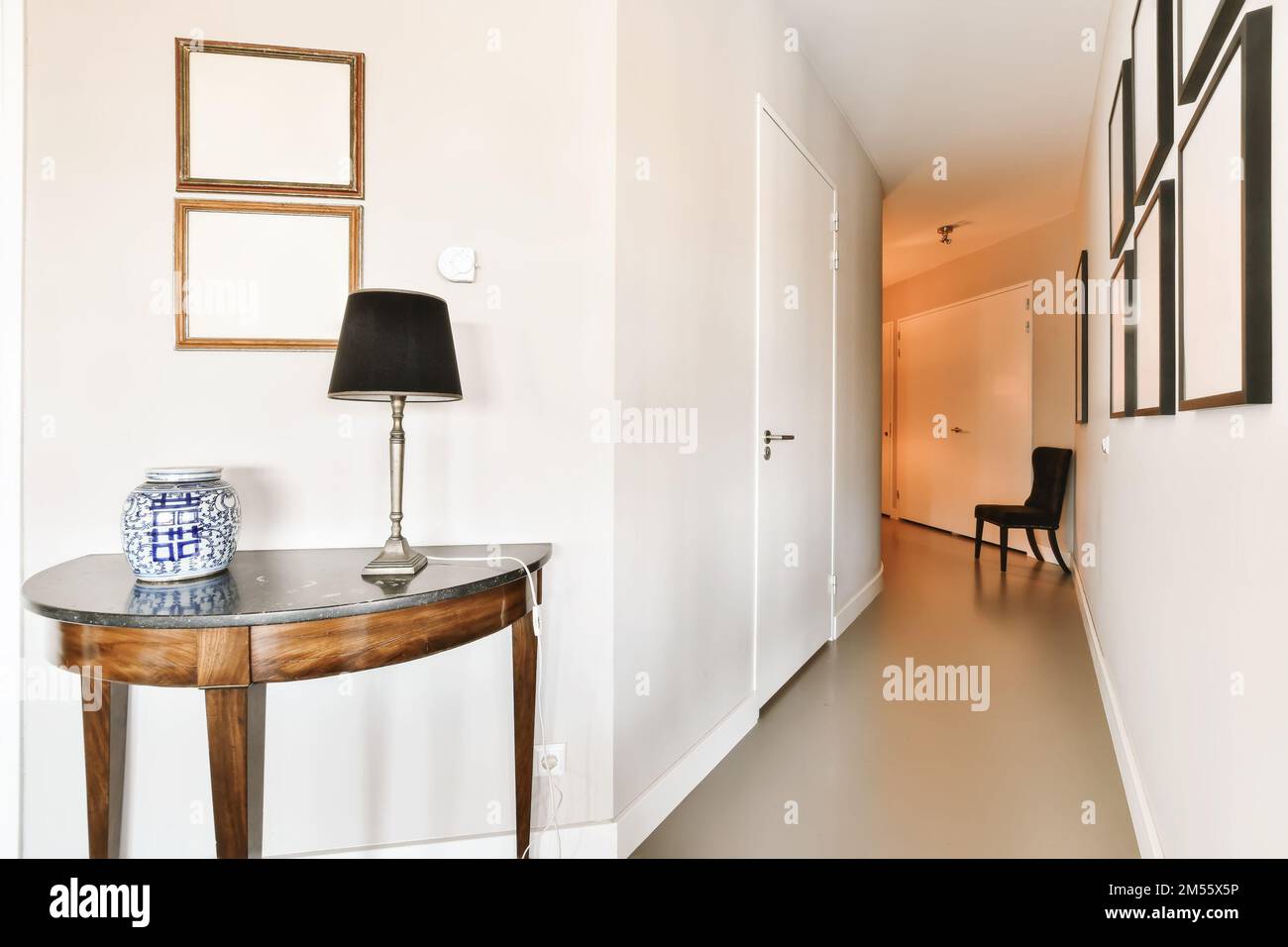 un couloir dans un appartement avec des murs blancs et du parquet sur le côté droit de la chambre est une petite table de console Banque D'Images