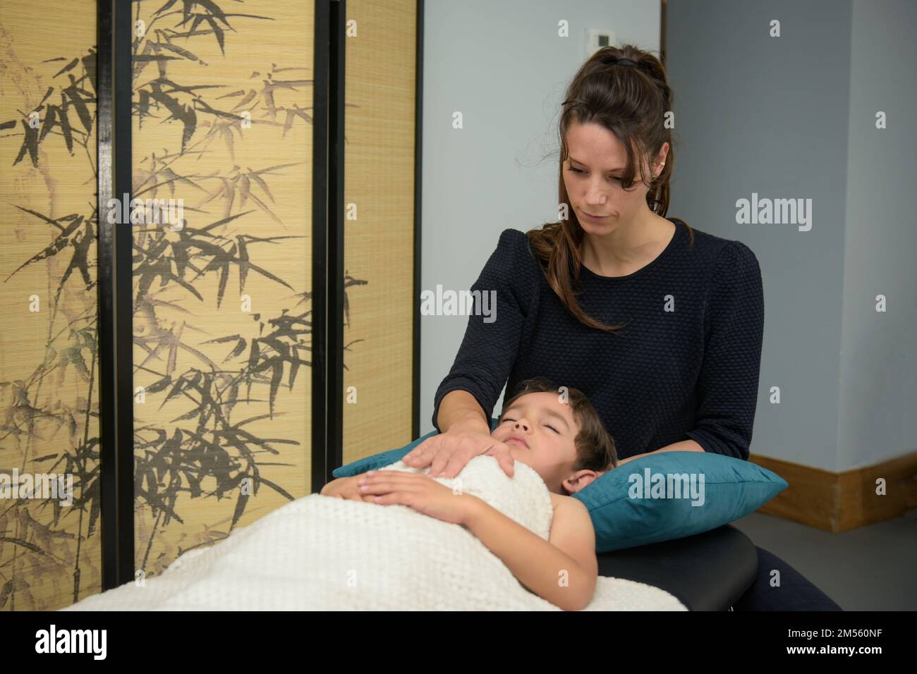Femme caucasienne pratiquant l'ostéopathie sur un enfant dans son bureau Banque D'Images