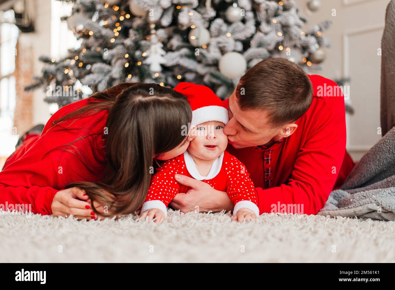 Noël famille embrassant et embrassant. L'enfant a surpris sa mère et son père avec un cadeau de Noël. Famille près de l'arbre de noël. Joyeux Noël et Banque D'Images