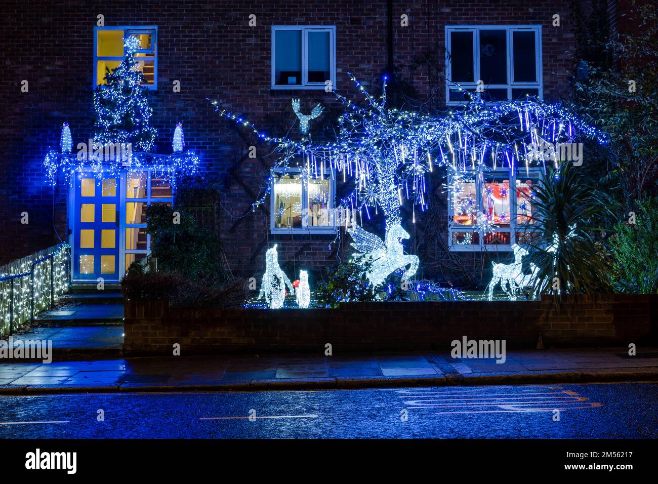 Un Pegasus blanc éclatant et une famille de rennes parmi les décorations de Noël à l'extérieur d'un immeuble d'appartements au Royaume-Uni la nuit. Banque D'Images