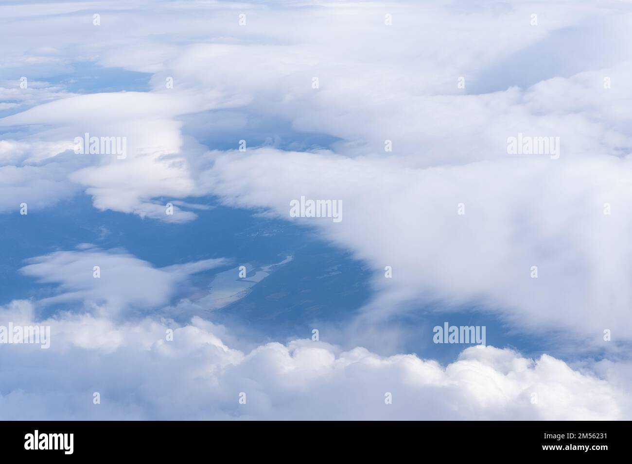 La vue de la fenêtre de plan aux nuages et au sol. Le paysage de la surface de la terre, visible depuis un avion sous des nuages blancs et des blu Banque D'Images