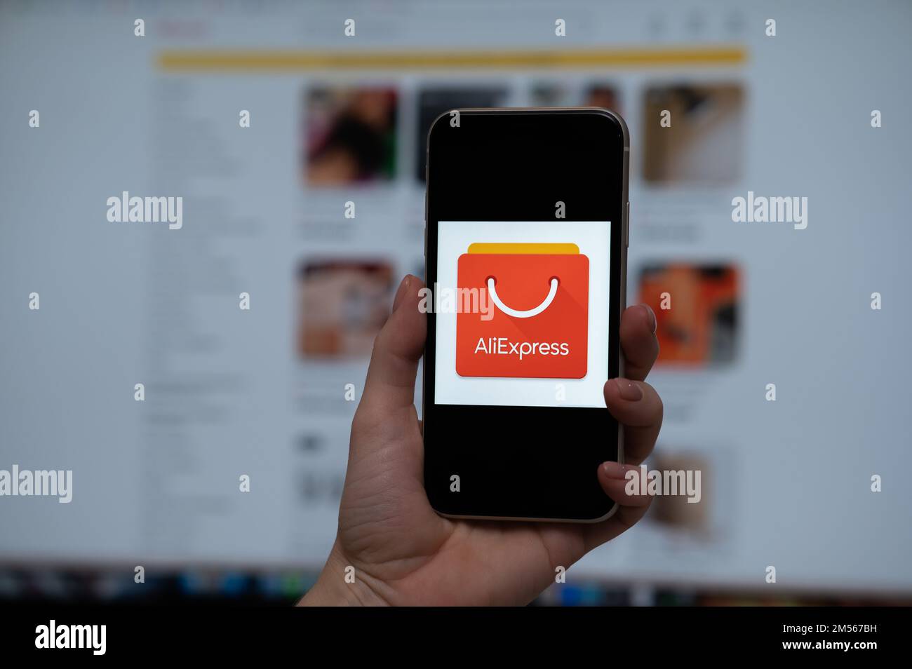 3 décembre 2022 Almaty Kazakhstan: Une femme sans visage tient un smartphone avec le logo Ali Express sur l'arrière-plan du moniteur. Banque D'Images