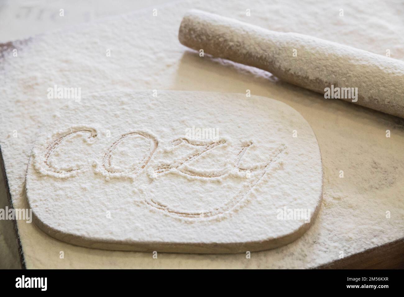 Le mot cosy écrit en farine sur la table de cuisine Banque D'Images