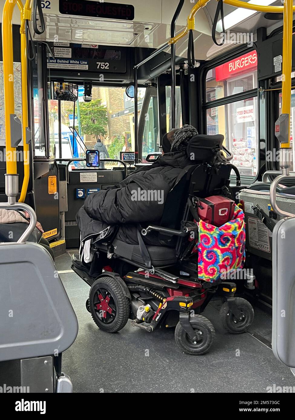 Femme en fauteuil roulant motorisé se préparant à sortir d'un bus MTA de la ville de New York équipé pour répondre aux besoins des personnes handicapées physiques. Banque D'Images