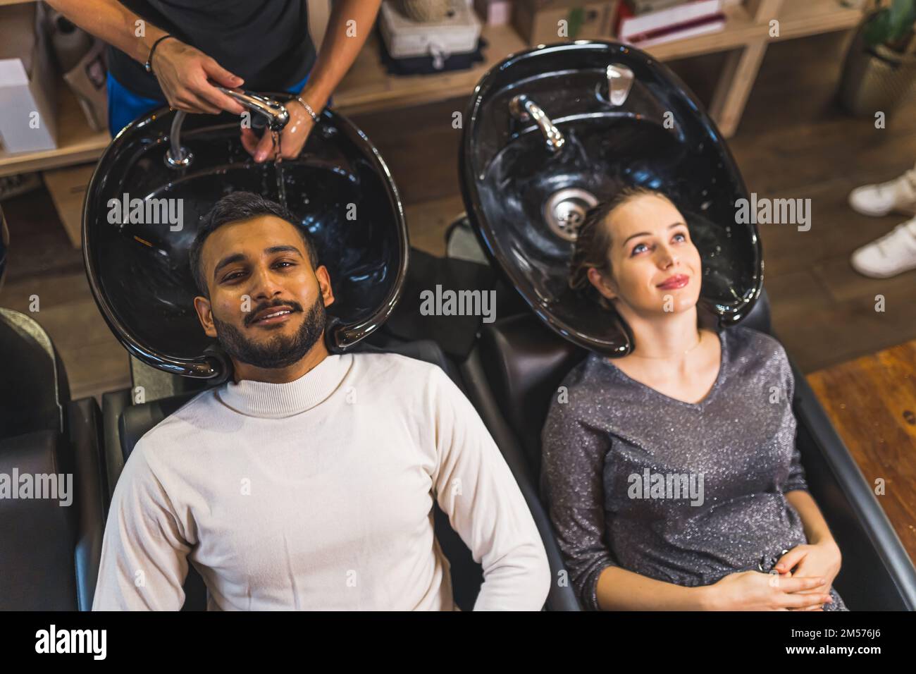 Lavage de cheveux au coiffeur - édition couple. Femme enceinte avec un  après-shampooing dans ses cheveux attendant que le coiffeur lave les  cheveux de son mari. Prise de vue en grand angle.