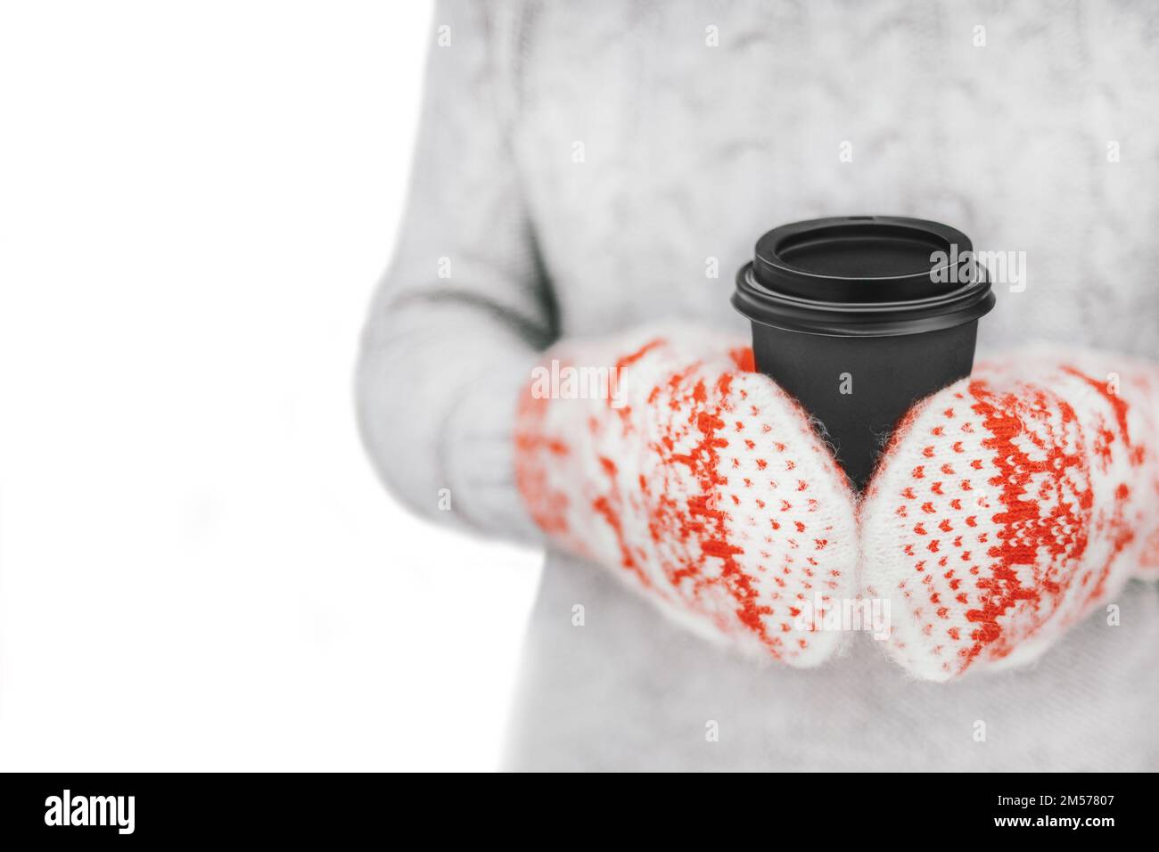Femme buvant du café chaud dans une tasse en papier. Concept de gel hiver saison.fille en fil mittens tenant la tasse noire dans ses mains sur fond blanc. PH Banque D'Images