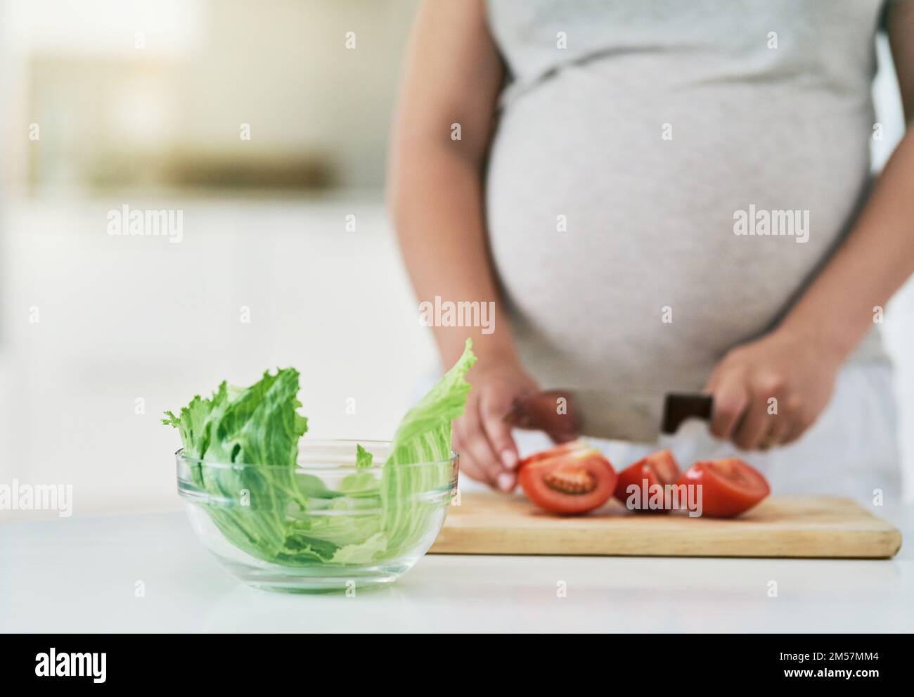 Une alimentation saine pendant la grossesse est essentielle à la croissance de votre babilys. une femme enceinte qui fait une salade. Banque D'Images