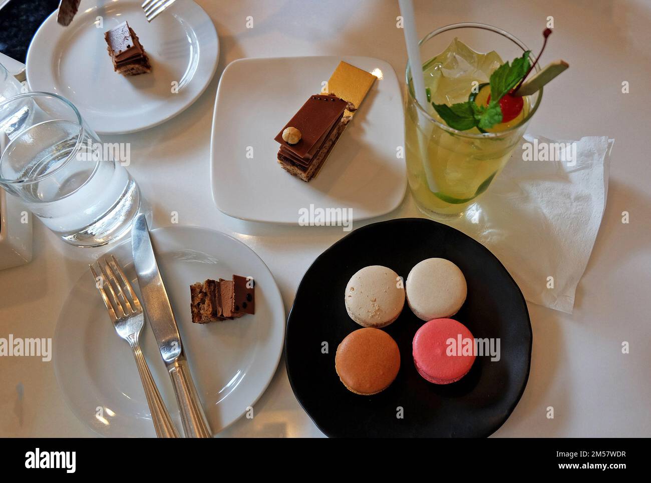 Gâteau d'opéra au chocolat français et assortiment de macarons (macarons) servis avec de la limonade glacée Banque D'Images