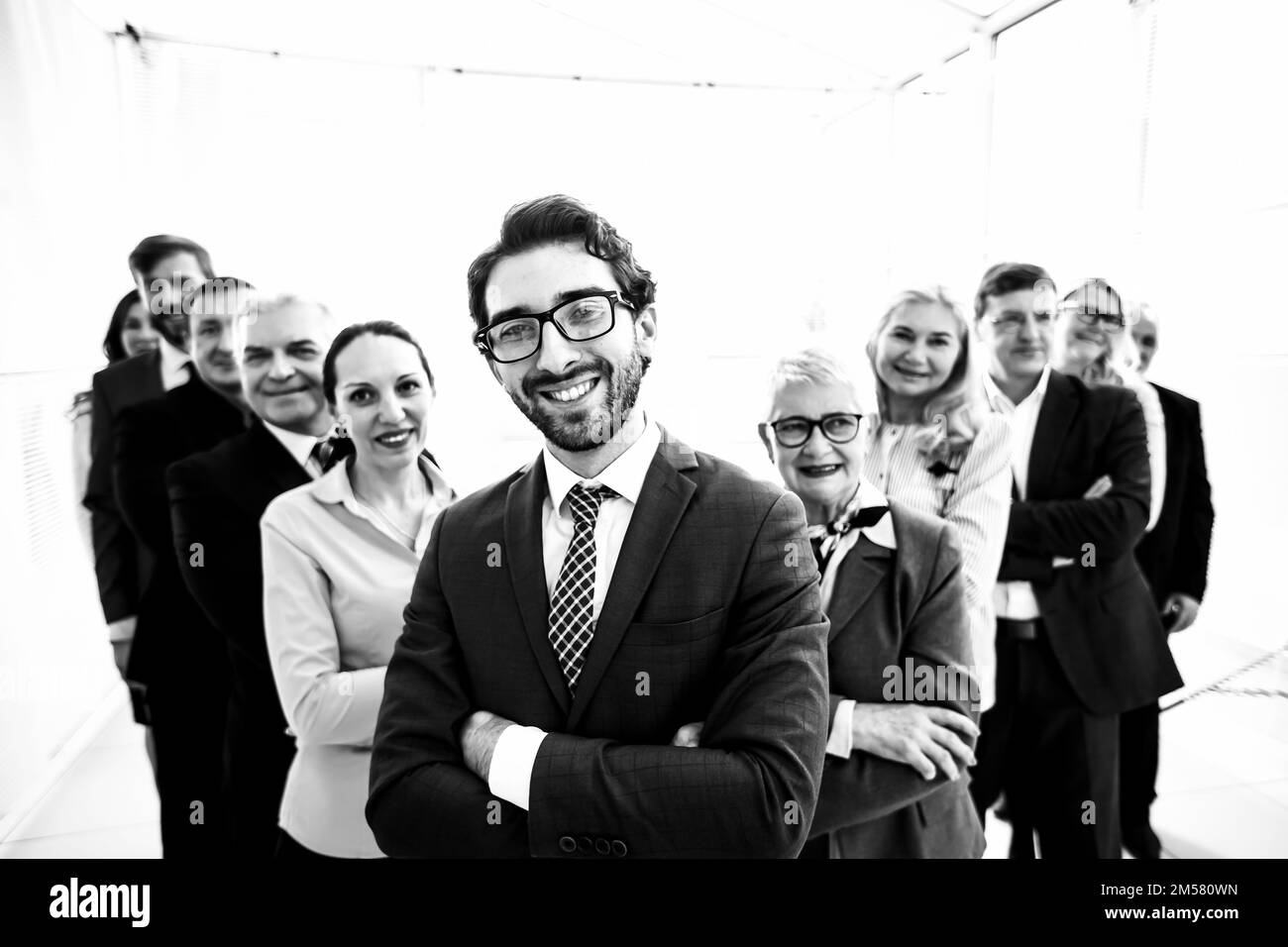 gros plan. homme d'affaires souriant devant une grande équipe d'affaires. photo en noir et blanc. Banque D'Images