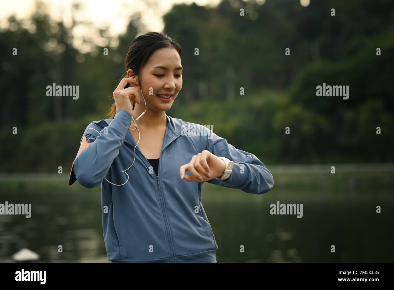 Femme sportive qui vérifie ses données de fréquence cardiaque sur une montre intelligente après avoir été au parc. Concept de mode de vie sain Banque D'Images