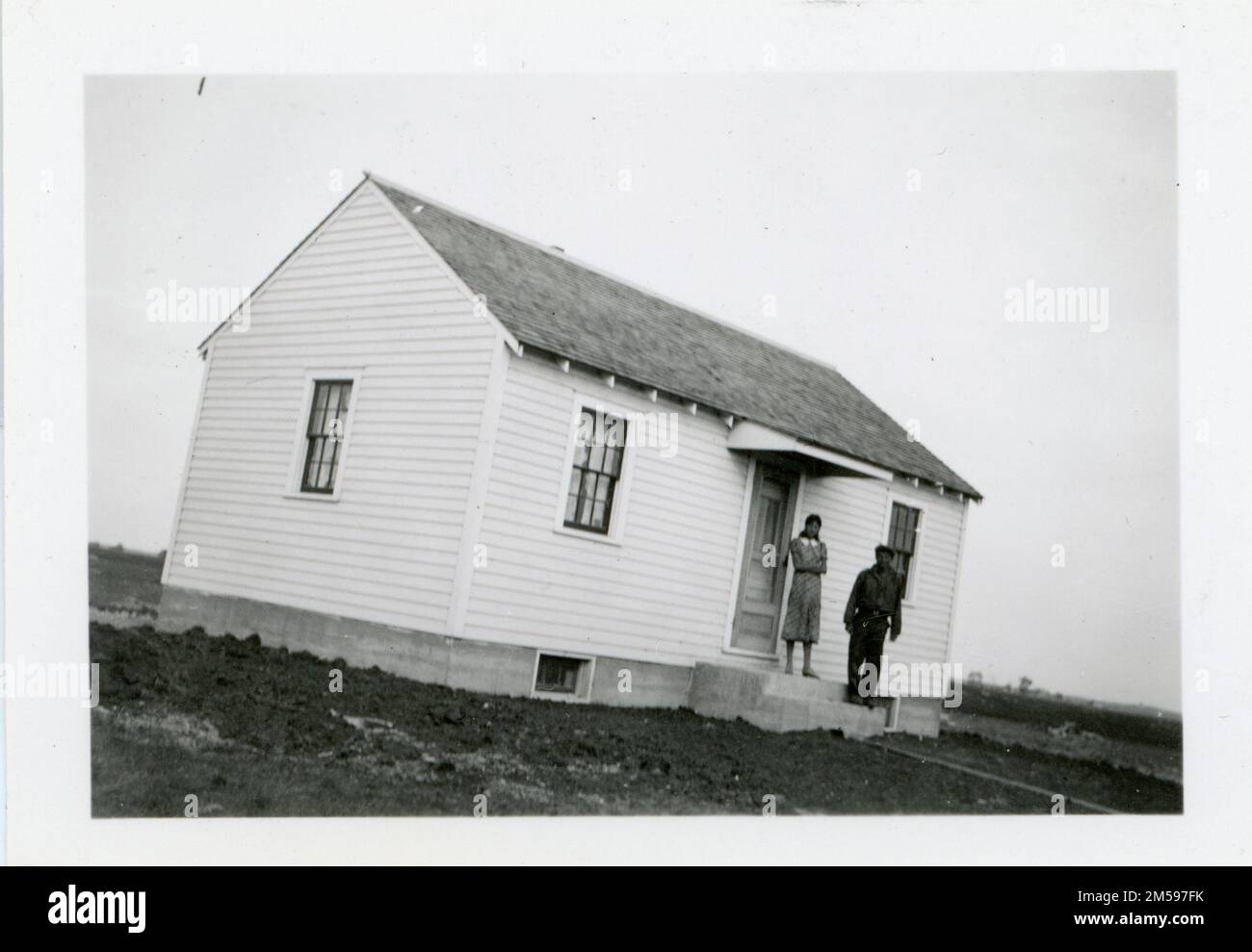 Matt Gill et la femme sur le porche avant de la maison terminée. 1920 - 1965. Région des Plaines centrales (Kansas City, Mo). Impression photographique. Département de l'intérieur. Bureau des affaires indiennes. Agence Sisseton. 9/17/1947-. Photographies Banque D'Images