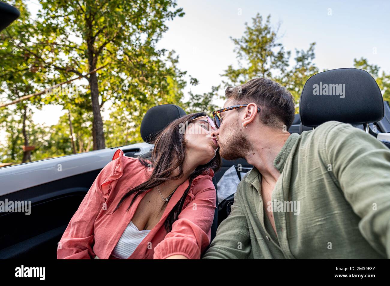 Soyez ma Saint-Valentin, jeune couple amour baiser portrait, voyage de route pour lune de miel, grilfriend et petits amis embrassant dans une voiture convertible Banque D'Images