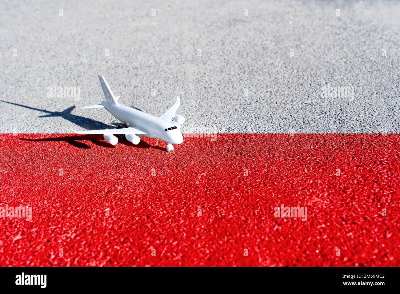L'avion jouet placé sur la route peint les couleurs du drapeau national de la Pologne. Banque D'Images