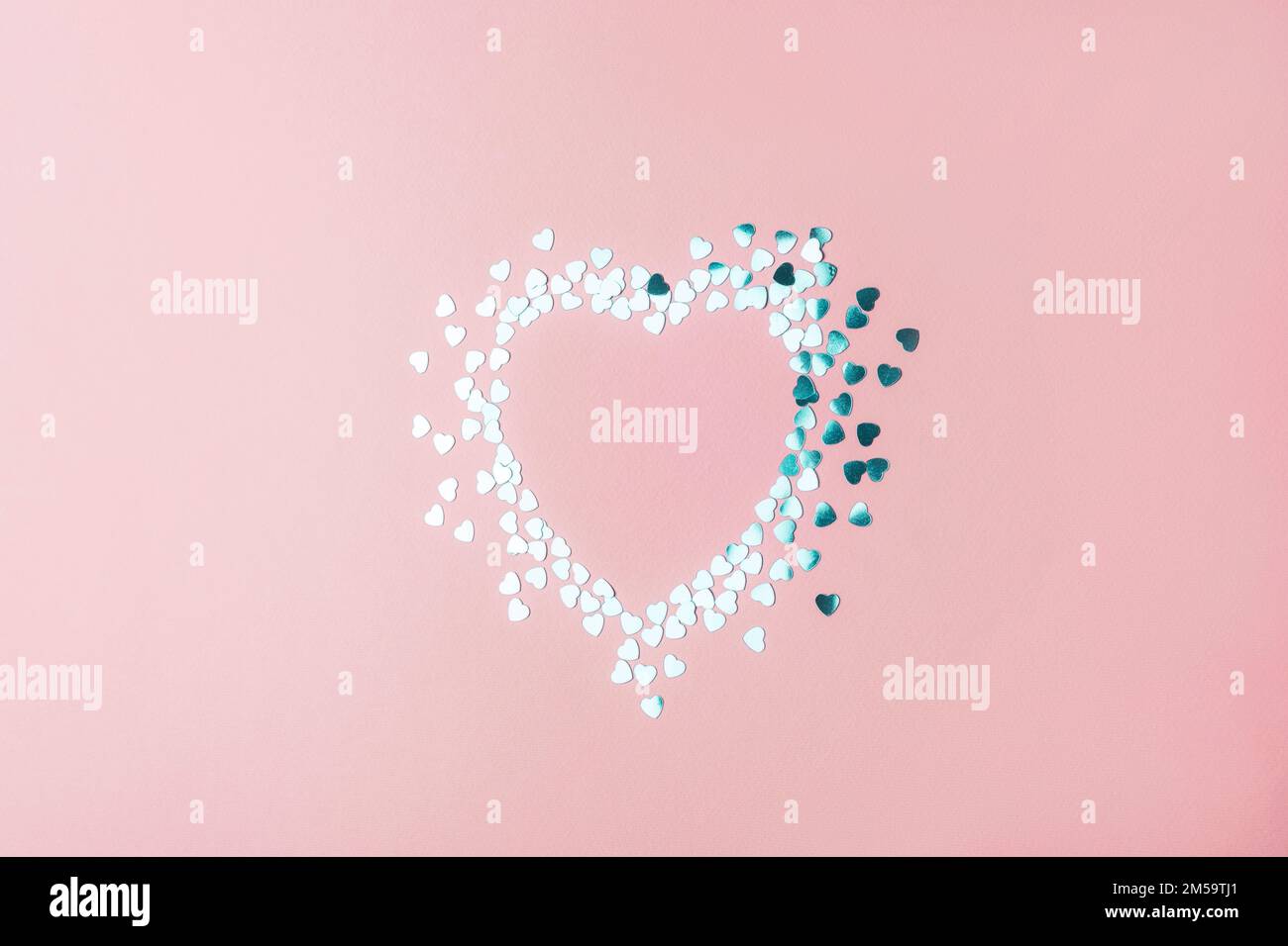 Coeur en confettis d'argent sur fond rose. Concept de vacances de Saint-Valentin. Maquette. Banque D'Images