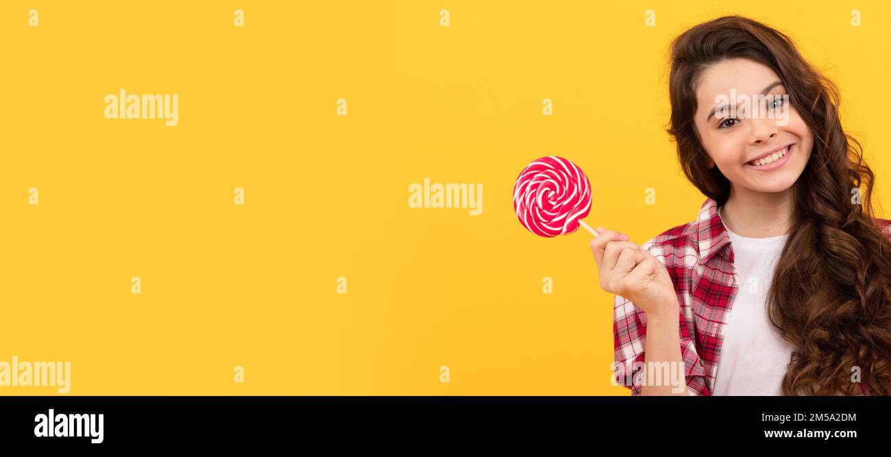 drôle enfant tenir lollipop caramel bonbon sur fond jaune montrer le geste de paix. Adolescent avec bonbons, affiche en-tête de bannière, espace de copie. Banque D'Images