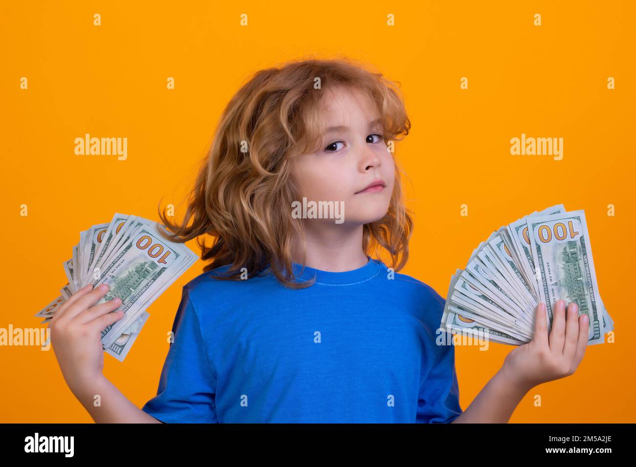 Enfant ayant beaucoup de cent dollars isolés sur fond jaune. Banque D'Images