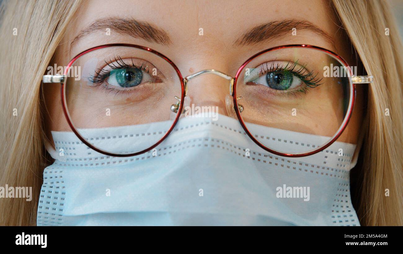 Extrême gros plan femme visage caucasien fille avec les yeux bleus porter des lunettes et un masque médical femme médecin infirmière travailleur de laboratoire dans respirateur et Banque D'Images