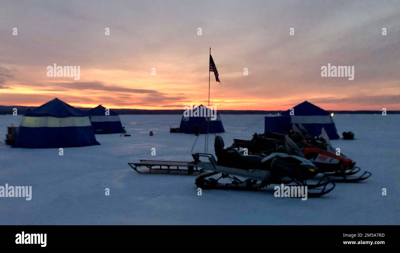 Le soleil se couche sur un camp érigé sur la glace du lac Great Sacandaga près de Northville, New York, le 15 février 2022 par des aviateurs de l'aile 109th du transport aérien de la garde nationale de l'air de New York. Les aviateurs s'étaient formés sur les tâches liées à la création d'une voie de glace pour atterrir sur glace un énorme avion LC-130 Hercules équipé de skis dans les régions polaires. Banque D'Images