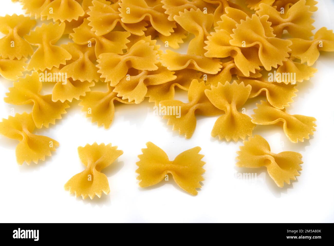 Pâtes italiennes sèches non cuites en forme de noeud papillon appelé  farfalle, isolées sur la vue de dessus blanche Photo Stock - Alamy