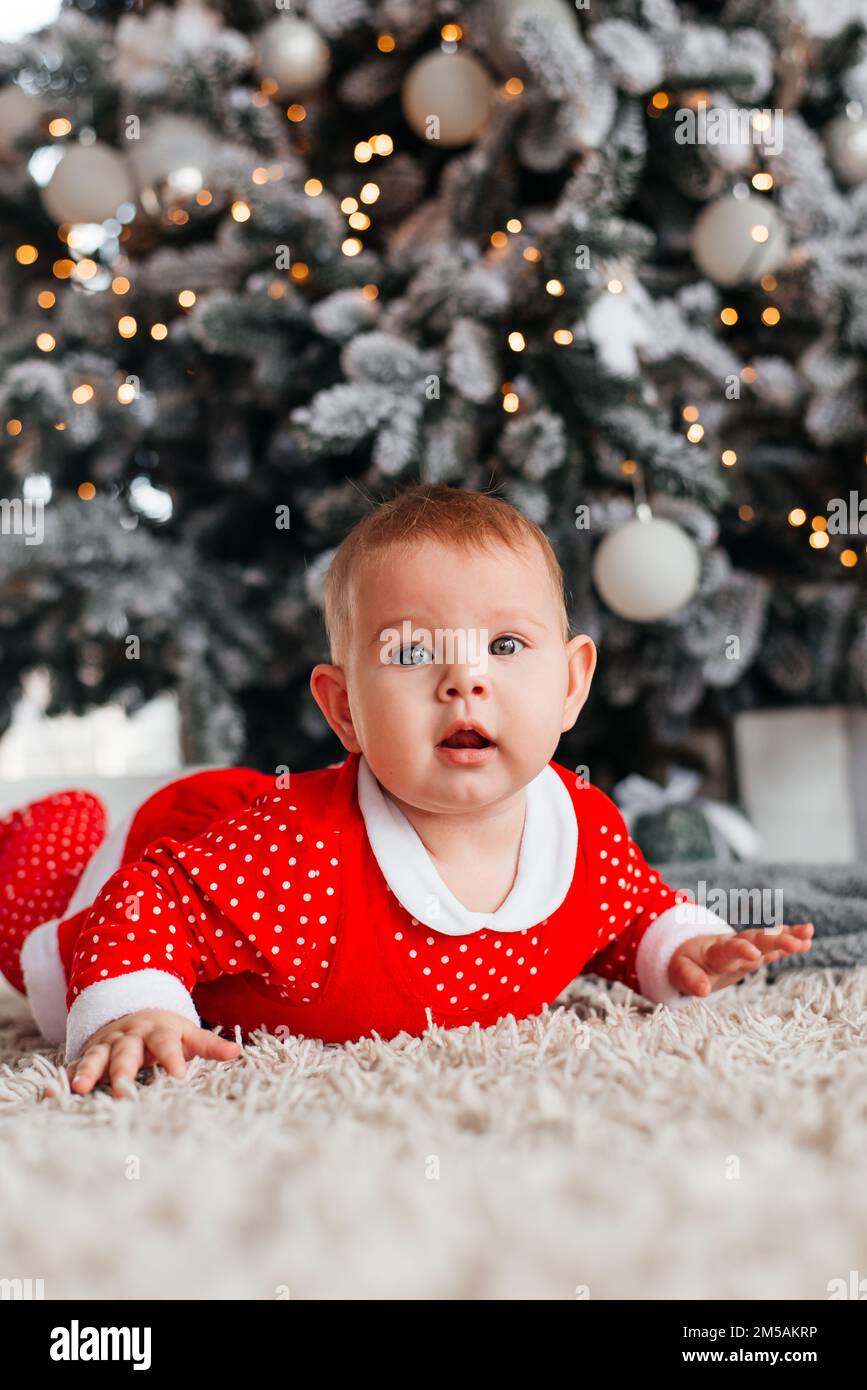 Petite fille enfant près de l'arbre de Noël dans un costume rouge Banque D'Images