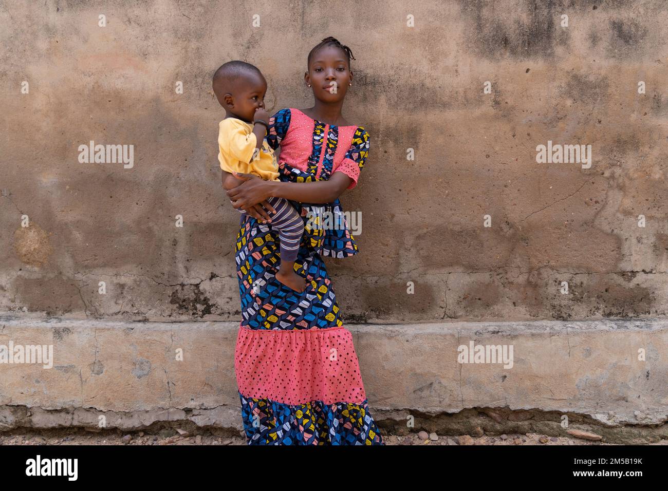 Une jeune fille africaine confiante qui prend soin de son petit frère ; concept d'inégalité des sexes Banque D'Images