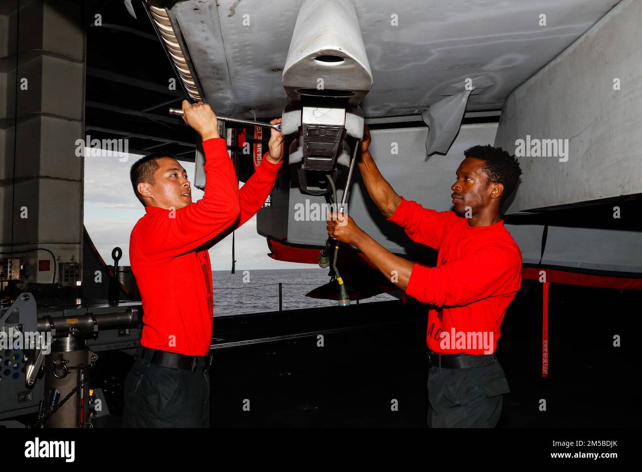 MER DES PHILIPPINES (20 février 2022) Aviation Ordnanceman 3rd Class Earl Guce, à gauche, de Las Vegas, et Aviation Ordnanceman Airman Joseph Rucker, de St. Louis, affecté aux “Black Aces” du Strike Fighter Squadron (VFA) 41, effectue l'entretien d'un F/A-18F Super Hornet dans la baie hangar à bord du porte-avions de la classe Nimitz USS Abraham Lincoln (CVN 72). Abraham Lincoln Strike Group est en cours de déploiement prévu dans la zone d'exploitation de la flotte américaine 7th afin d'améliorer l'interopérabilité par le biais d'alliances et de partenariats tout en servant de force de réaction prête à l'emploi pour soutenir un Indo-PAC libre et ouvert Banque D'Images