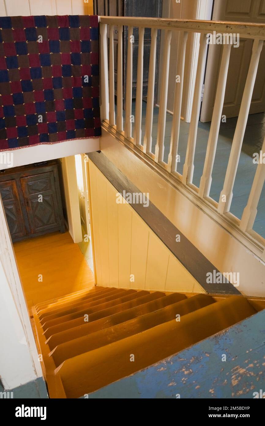 Balustrades d'escalier en bois blanc partiellement couvertes de couverture rouge et bleue o à l'étage à l'intérieur de la vieille maison 1722. Banque D'Images