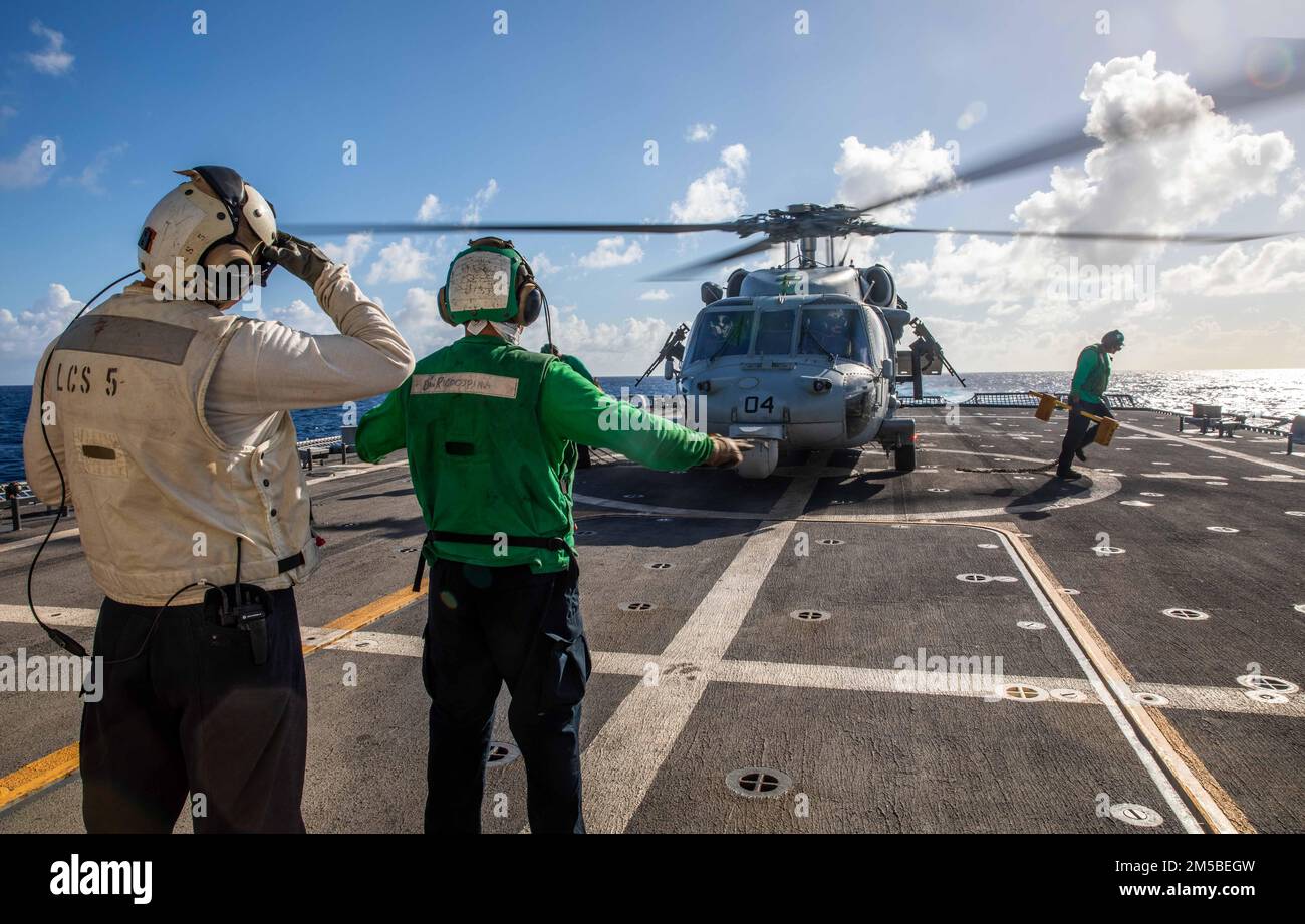220221-N-HD110-1018 MER DES CARAÏBES - (21 FÉVRIER 2022) -- Classe 2nd du compagnon de Boatswain James Dowdee observe le compagnon de machiniste de l’aviation Airman Felix Ricoospina signal aux marins de s’éloigner après avoir retiré des cales et des chaînes avant le décollage d’un hélicoptère MH-60s Sea Hawk attaché aux “Chevaliers de mer” de l’Escadron de combat de la mer (HSC) 22, détachement 5, À bord du navire de combat littoral Freedom-variant USS Milwaukee (LCS 5), lors d'un exercice d'utilisation aérienne de la force (AUF), le 21 février 2022. Milwaukee est déployé dans la zone d’opérations de la flotte US 4th pour soutenir la Force opérationnelle interagences interarmées Sud Banque D'Images