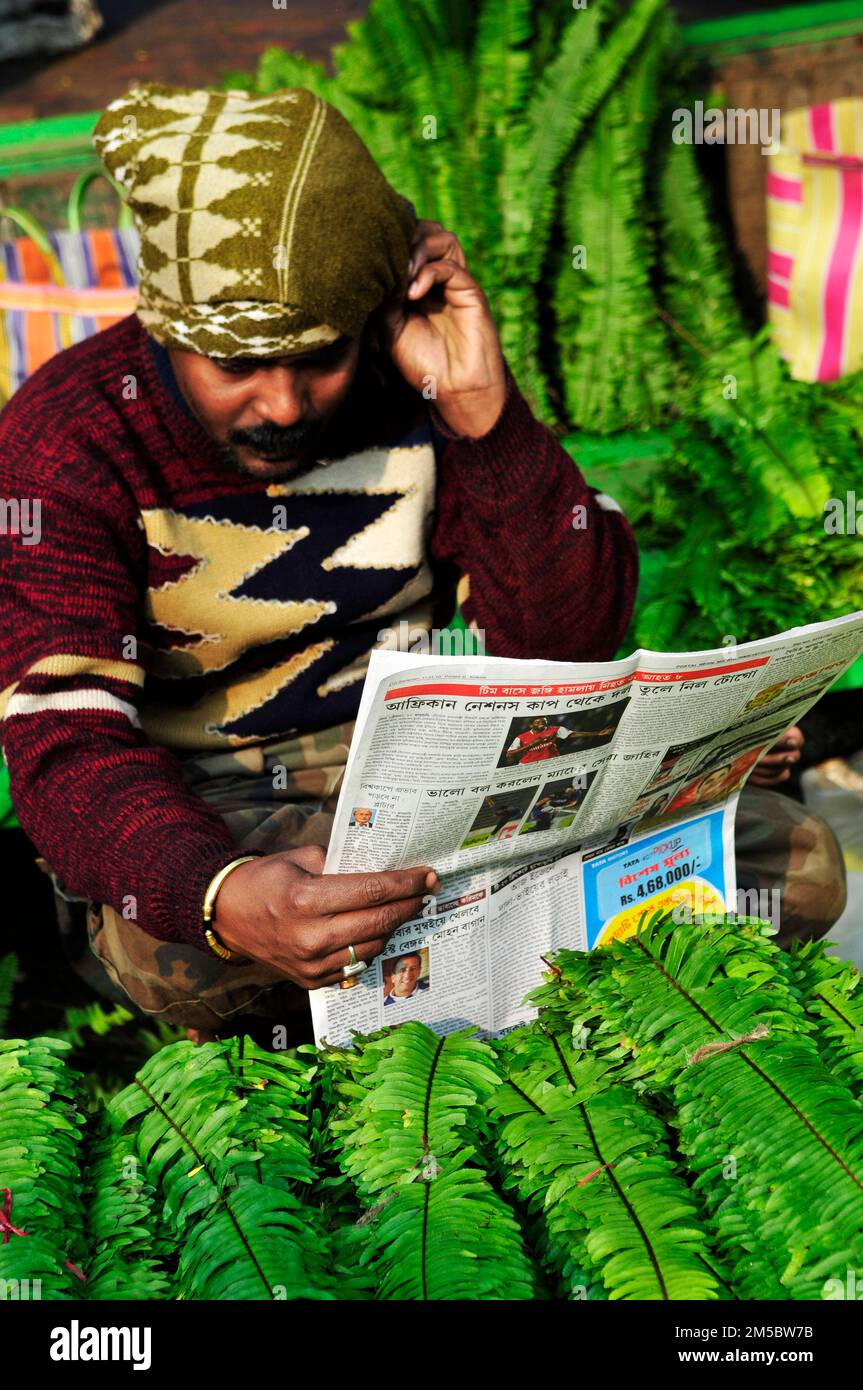 Un homme bengali lisant le journal du matin sur le marché de Kolkata, en Inde. Banque D'Images