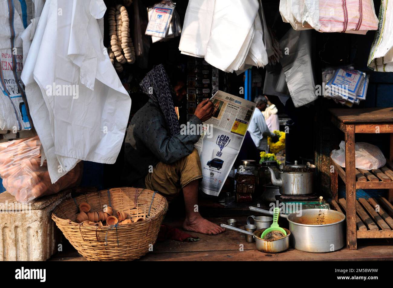 Un homme bengali lisant le journal du matin sur le marché de Kolkata, en Inde. Banque D'Images