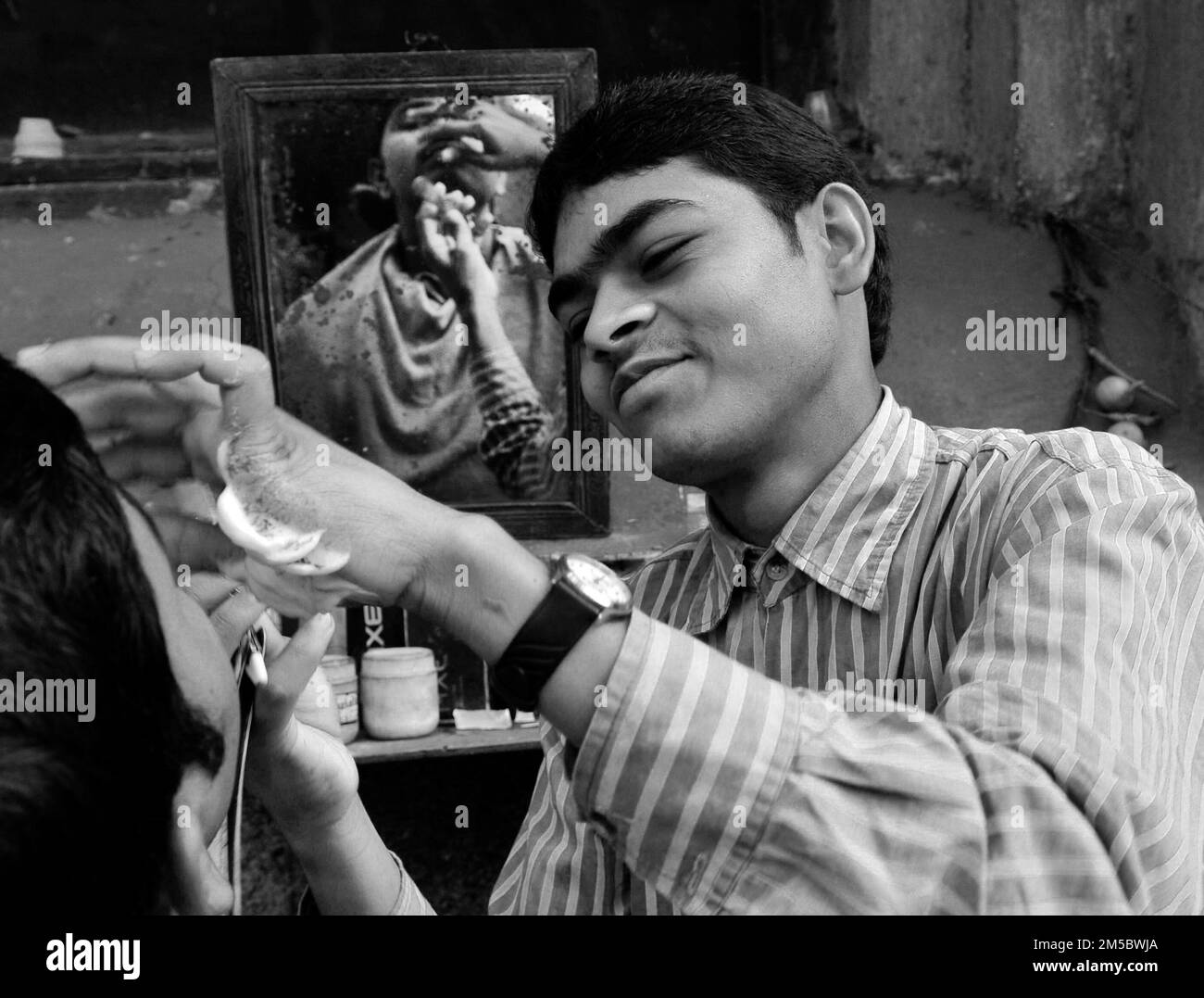 Un barbier de rue rave un homme à Kolkata, Inde. Banque D'Images