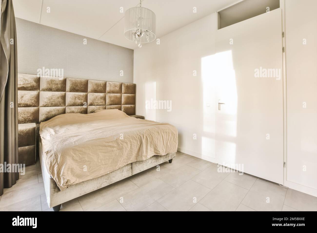 une chambre avec un lit et une chandel sur le mur en face du lit est une porte ouverte Banque D'Images