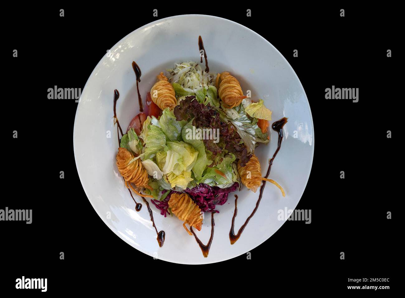Salade mixte avec crevettes dans un nid de pommes de terre sur fond noir, Bavière, Allemagne Banque D'Images