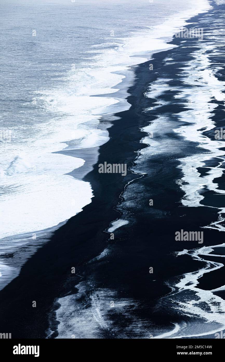 Vagues blanches mourantes et surfaces glacées sur la plage de galets noirs Skogarsandur, près de Dyrholaey, Sudurland, Islande Banque D'Images