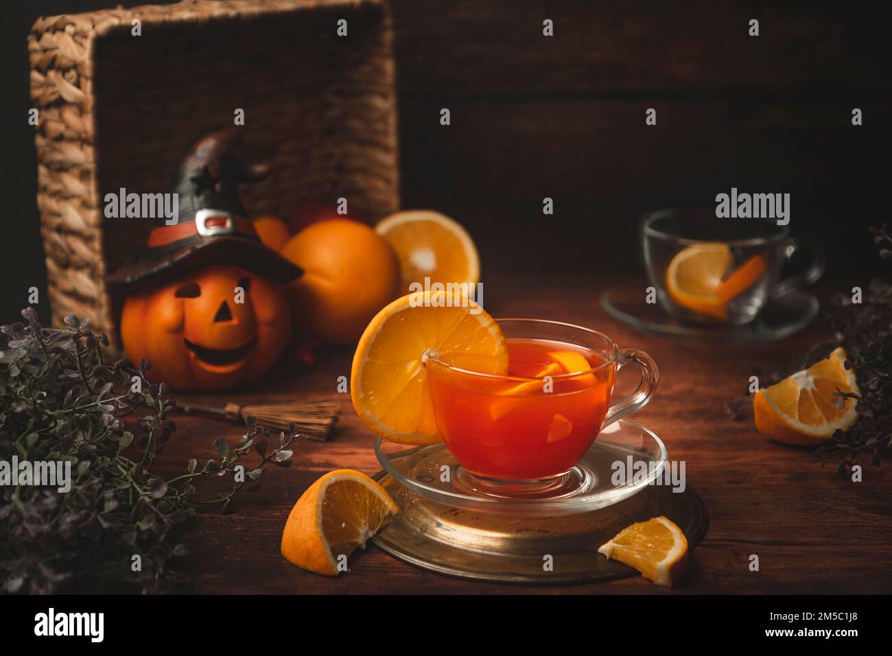 Thé à l'orange dans la tasse, sur fond de bois, devant la décoration d'Halloween Banque D'Images