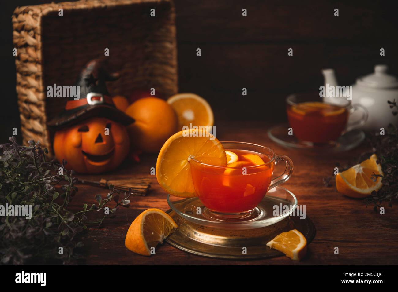 Thé à l'orange dans la tasse, sur fond de bois, devant la décoration d'Halloween Banque D'Images