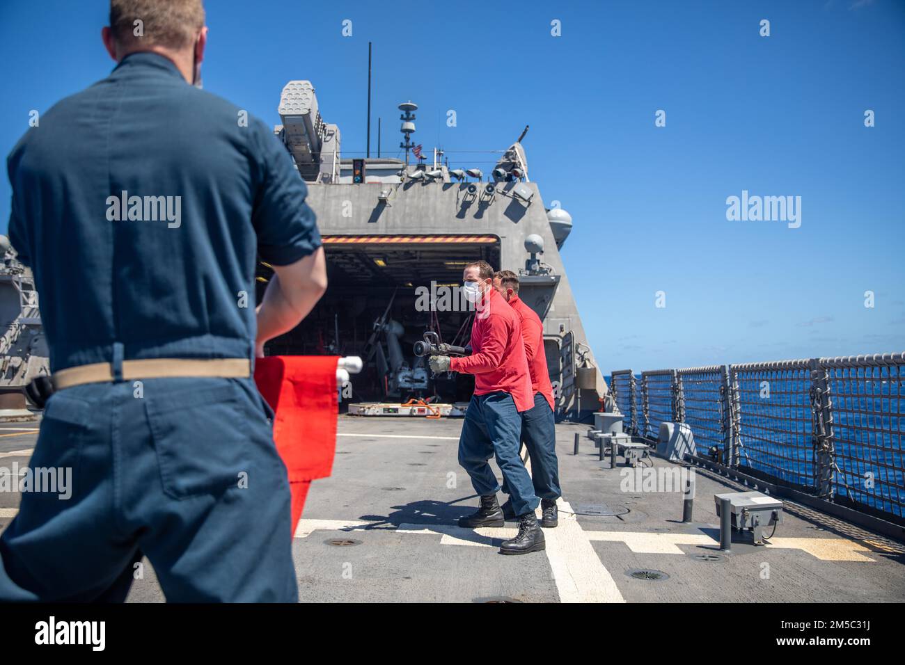 220225-N-HD110-1057 MER DES CARAÏBES - (25 FÉVRIER 2022) -- Le chef des dégâts Controlman Slavik Verbovoskiy, à gauche, maintient des drapeaux simulant un incendie tandis que le compagnon du chef Gunner Stephen Rose et le compagnon du chef Gunner Richard Zitzke simulent la mise en place lors d’un exercice de lutte contre les incendies sur le pont de vol à bord du navire de combat littoral Freedom-variant USS Milwaukee (LCS 5), le 25 février 2022. Milwaukee est déployée dans la zone d’opérations de la flotte américaine 4th pour appuyer la mission de la Force opérationnelle interagences conjointe Sud, qui comprend des missions de lutte contre le trafic de drogues illicites dans les Caraïbes et le Pacifique oriental. Banque D'Images