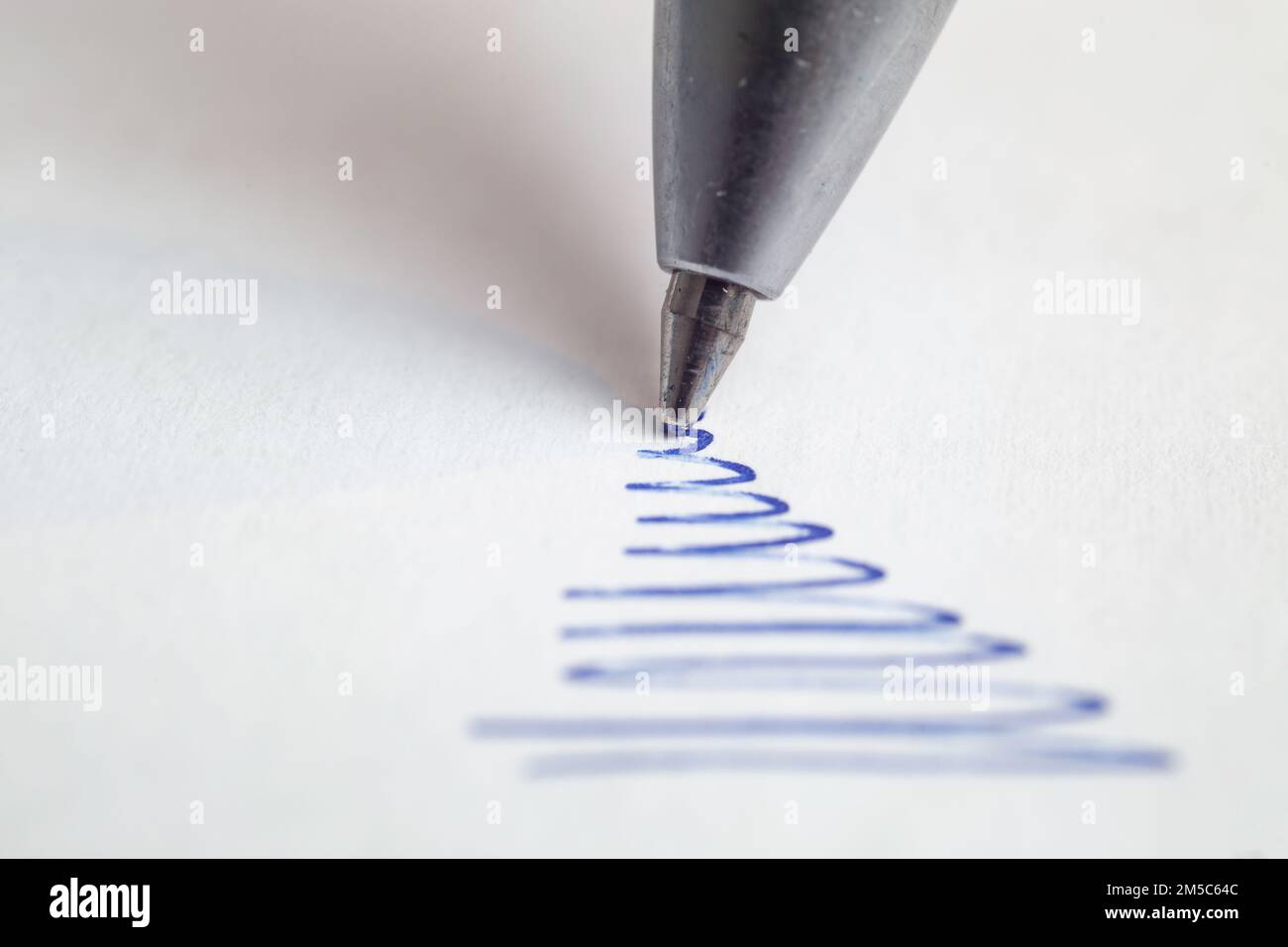 Stylo à bille bleu griffant sur papier blanc, macro de mise au point douce Banque D'Images
