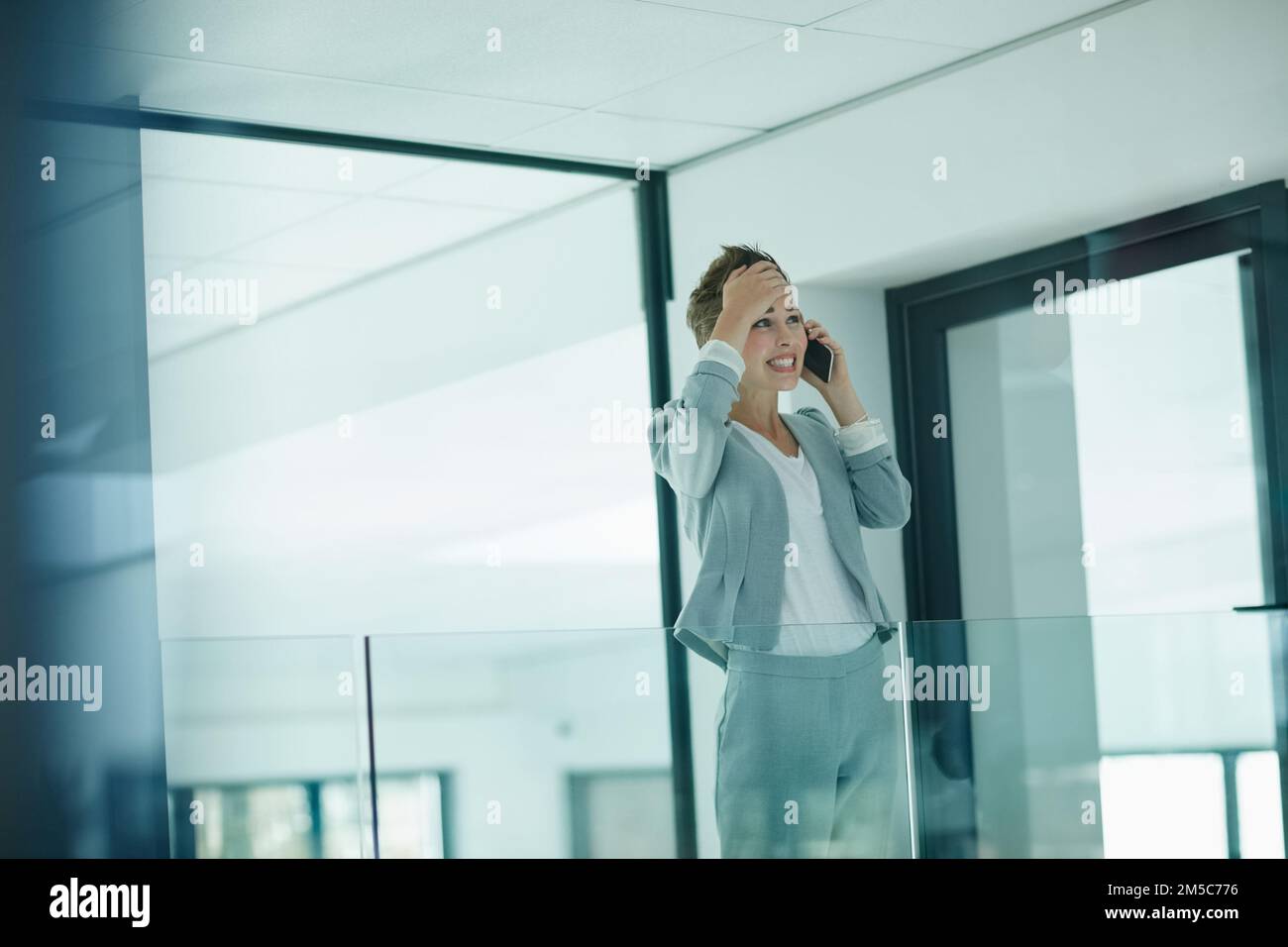 Oh, j'ai complètement oublié. une jeune femme d'affaires qui a l'air inquiète en parlant sur un téléphone portable dans un bureau. Banque D'Images