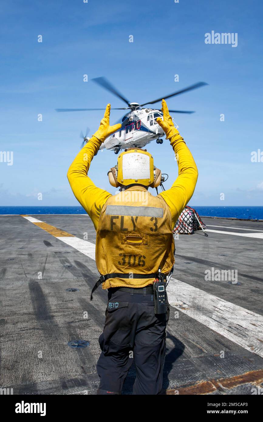 MER DES PHILIPPINES (1 mars 2022) Aviation Boatswain's Mate (Handling) 2nd classe Alasdair Reid, de Wellington, Nouvelle-Zélande, dirige un Super Puma AS332 sur le pont de vol du porte-avions de la classe Nimitz Abraham USS Lincoln (CVN 72) Lors d'un réapprovisionnement en mer avec le navire de fret sec et de munitions du Commandement du Seallift militaire USNS Matthew Perry (T-AKE 9). Abraham Lincoln Strike Group est en cours de déploiement prévu dans la zone d'exploitation de la flotte américaine 7th afin d'améliorer l'interopérabilité par le biais d'alliances et de partenariats tout en servant de force de réaction prête à l'emploi pour soutenir un Indo-PAC libre et ouvert Banque D'Images