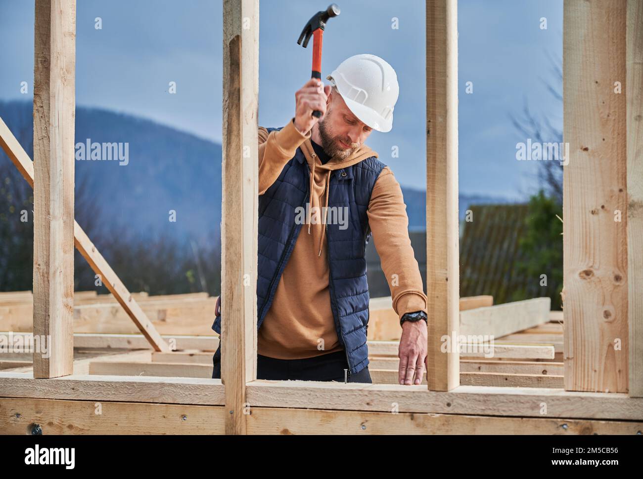 Homme ouvrier bâtiment maison en bois cadre. Clou de martelage de menuisier dans une planche en bois, à l'aide d'un marteau. Concept de menuiserie. Banque D'Images