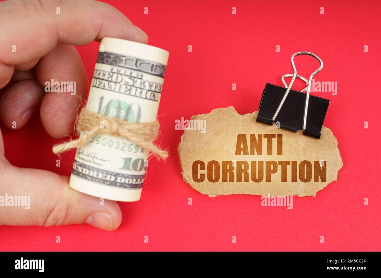 Concept d'entreprise. L'homme a des dollars dans ses mains, sur une surface rouge il y a un panneau en carton avec l'inscription - anti corruption Banque D'Images