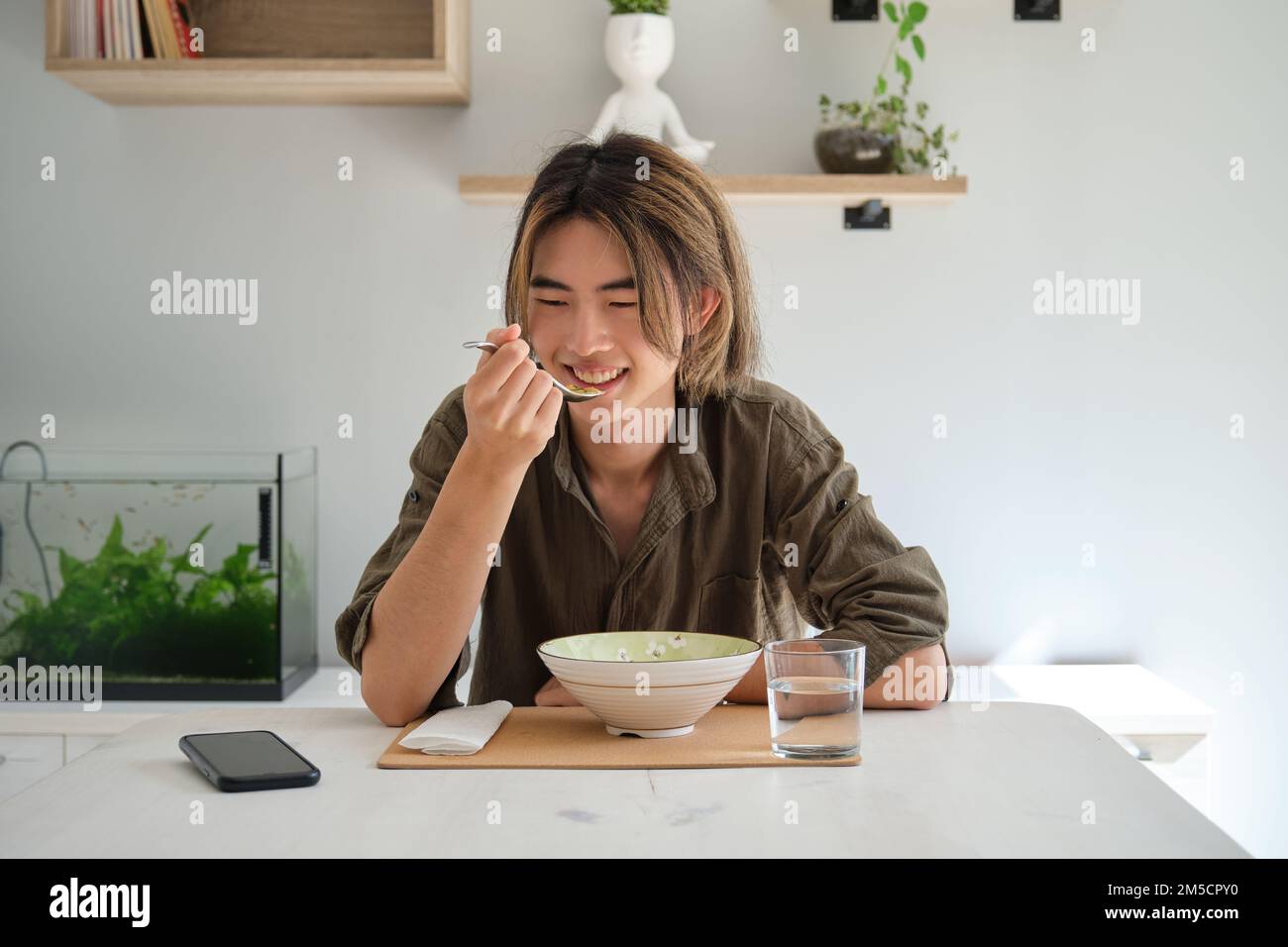 Un jeune homme taïwanais mange de la soupe dans le salon. Banque D'Images