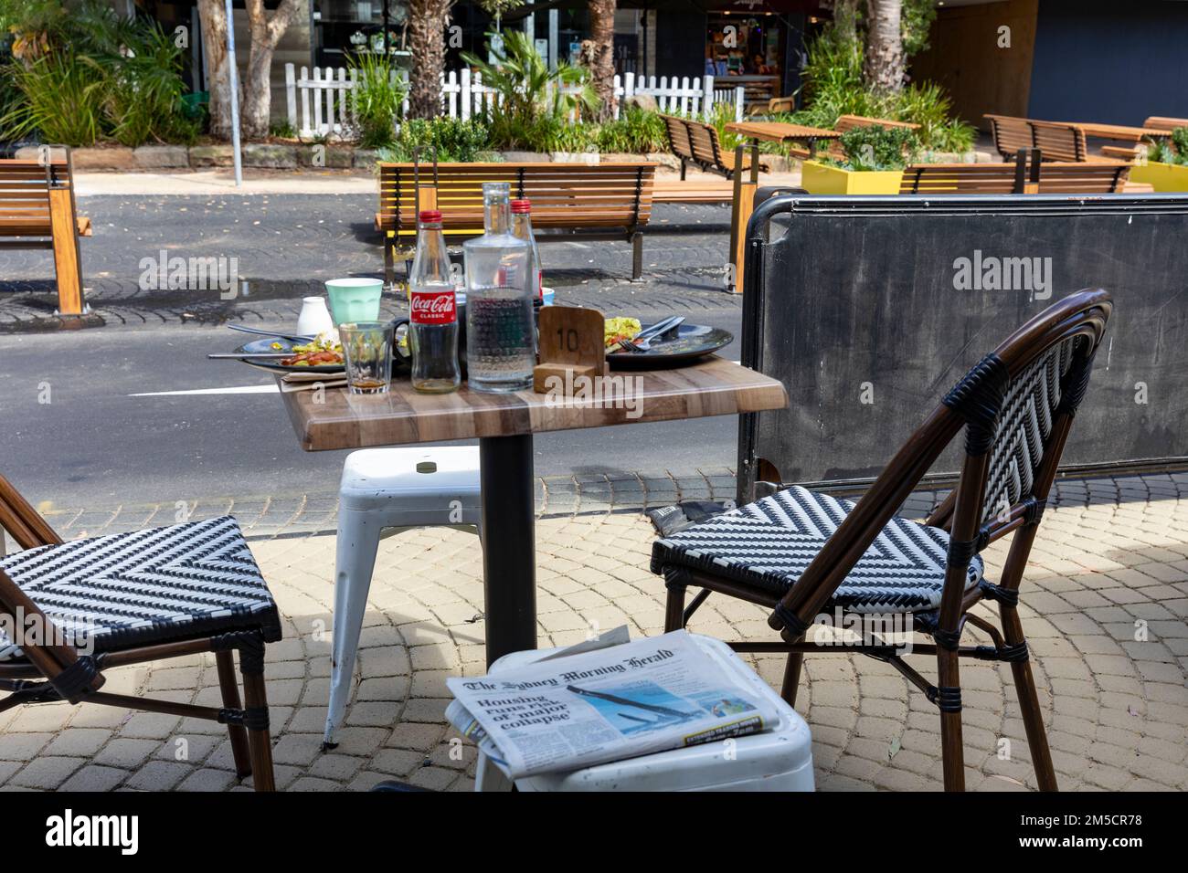 Table de petit-déjeuner dans un café à Avalon Beach Sydney avec les restes de nourriture, bouteille de coca vide et tasses de café, NSW, Australie Banque D'Images