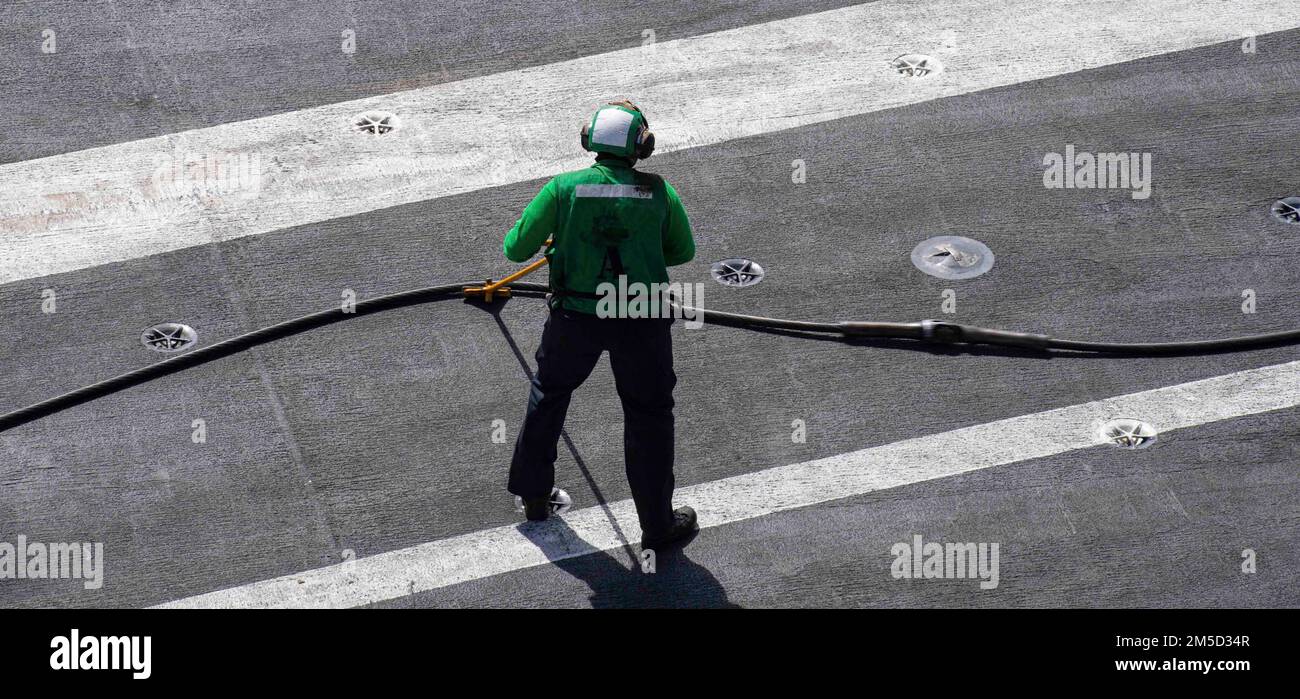 220303-N-LY692-1120 OCÉAN PACIFIQUE (Mar. 03, 2022) Sailor rétracte un câble d'équipement avec une barre de poussée sur le plateau de vol du porte-avions USS Nimitz (CVN68). Nimitz mène actuellement des opérations de routine. Banque D'Images