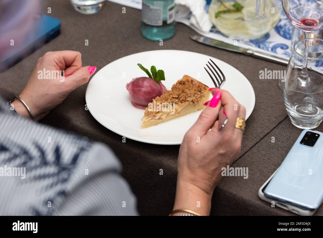 femme qui va manger une petite portion de tarte aux pommes et sorbet dans un restaurant Banque D'Images